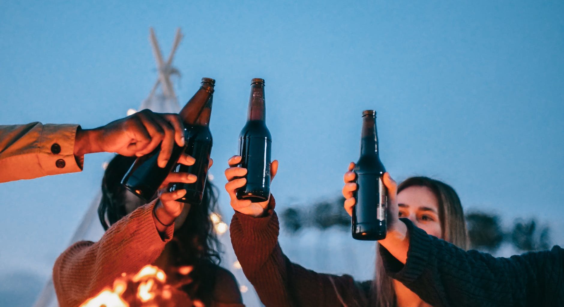 group of friends clinking beer bottles