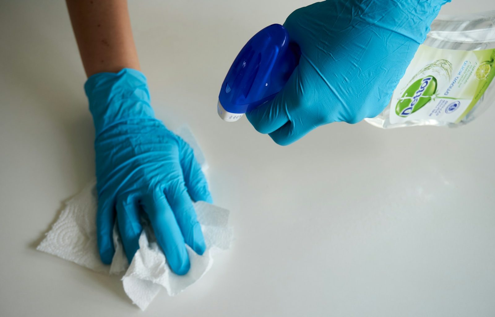 person in blue gloves holding white textile