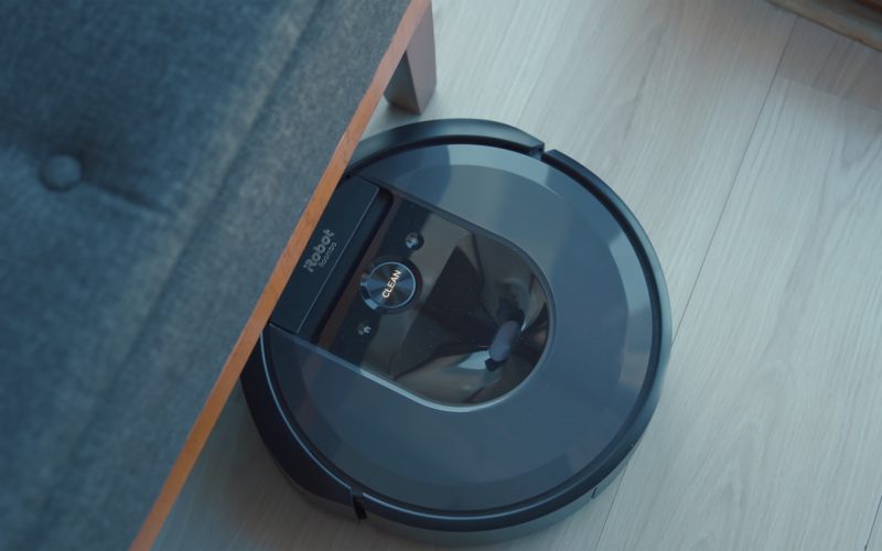 a robotic vacuum is on the floor next to a couch