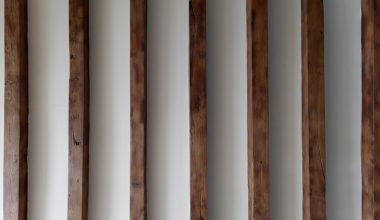 a row of wooden poles against a white wall