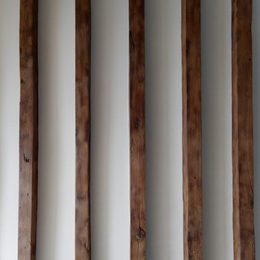 a row of wooden poles against a white wall