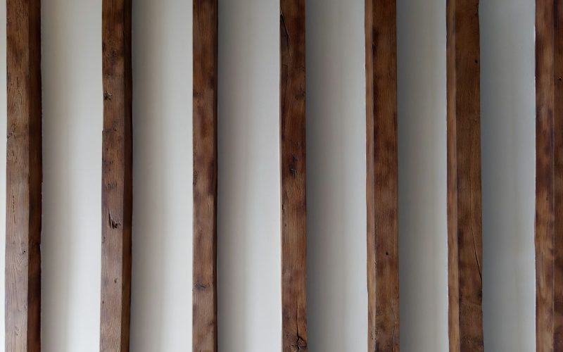 a row of wooden poles against a white wall