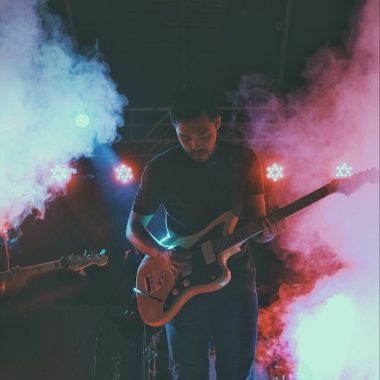 man in black crew neck t-shirt playing brown electric guitar