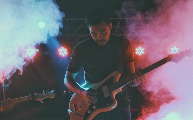 man in black crew neck t-shirt playing brown electric guitar