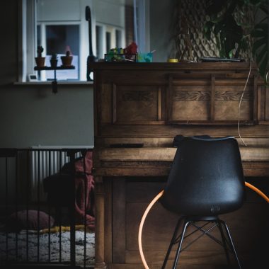 black leather chair beside brown wooden upright piano