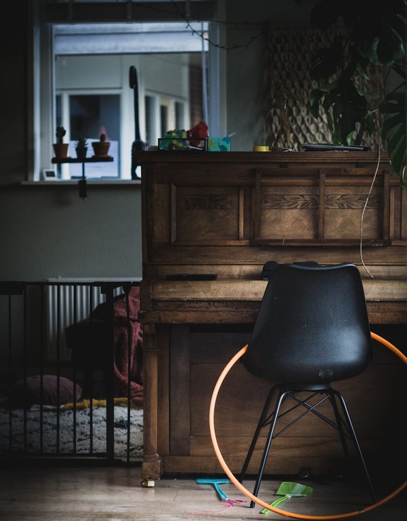 black leather chair beside brown wooden upright piano