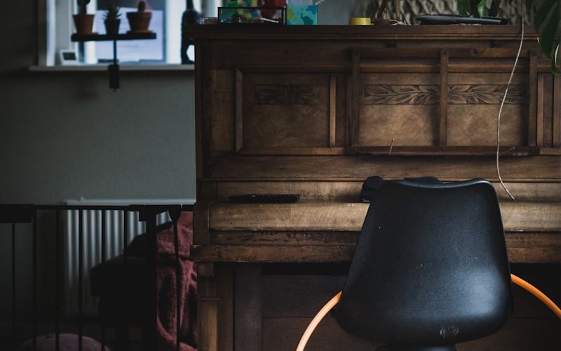 black leather chair beside brown wooden upright piano