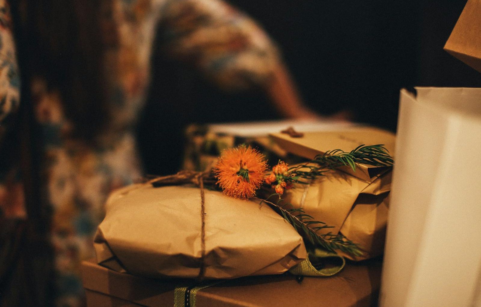 Warm-toned image of rustic wrapped gifts adorned with vibrant orange flowers, perfect for seasonal celebrations.