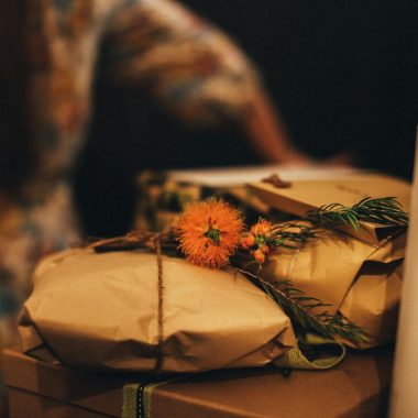 Warm-toned image of rustic wrapped gifts adorned with vibrant orange flowers, perfect for seasonal celebrations.