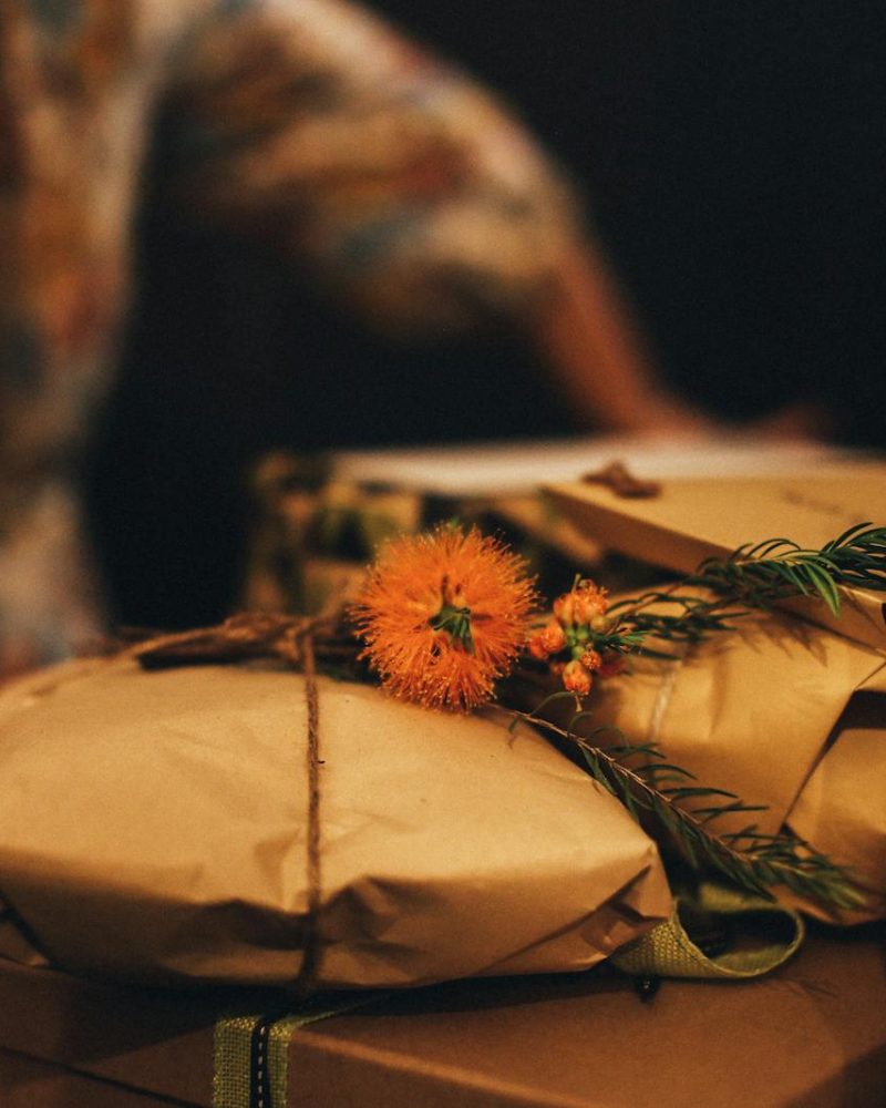 Warm-toned image of rustic wrapped gifts adorned with vibrant orange flowers, perfect for seasonal celebrations.