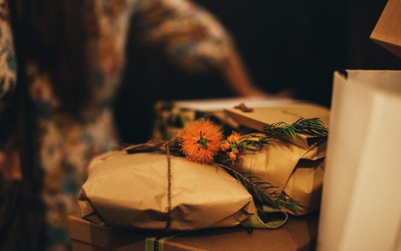 Warm-toned image of rustic wrapped gifts adorned with vibrant orange flowers, perfect for seasonal celebrations.