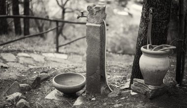 Persoon die een stenen waterornament in de tuin schoonmaakt met een borstel
