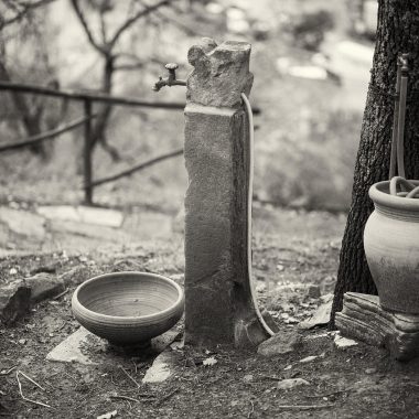 Persoon die een stenen waterornament in de tuin schoonmaakt met een borstel