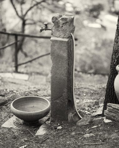 Persoon die een stenen waterornament in de tuin schoonmaakt met een borstel