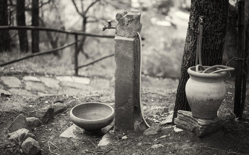 Persoon die een stenen waterornament in de tuin schoonmaakt met een borstel