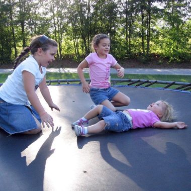 Kinderen springen op een trampoline in de tuin op een zonnige dag