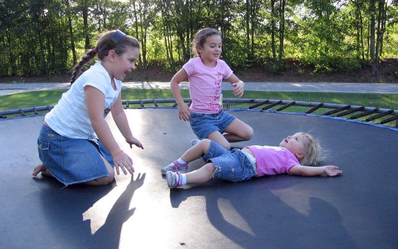 Kinderen springen op een trampoline in de tuin op een zonnige dag