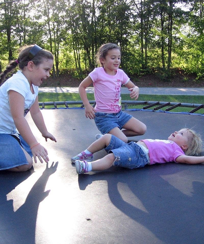Kinderen springen op een trampoline in de tuin op een zonnige dag