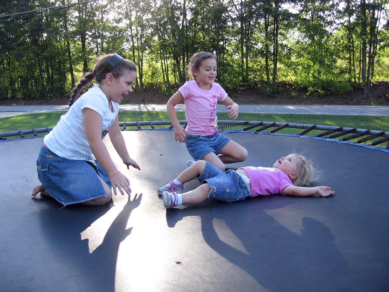 Kinderen springen op een trampoline in de tuin op een zonnige dag