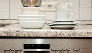 Een installateur plaatst een vaatwasser in een moderne keuken