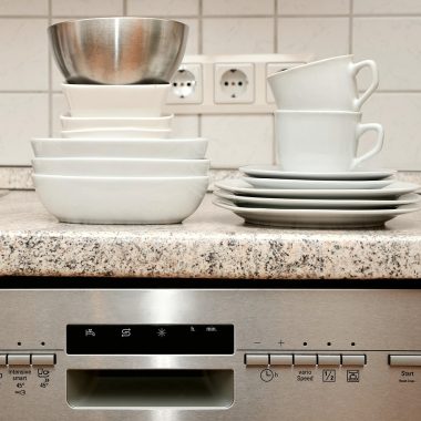 Een installateur plaatst een vaatwasser in een moderne keuken