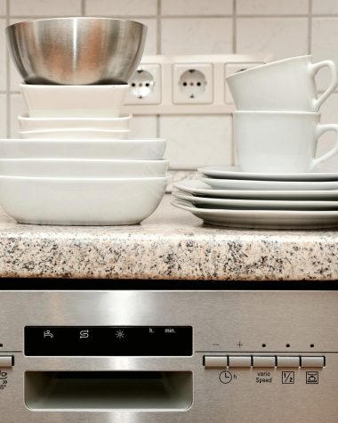 Een installateur plaatst een vaatwasser in een moderne keuken