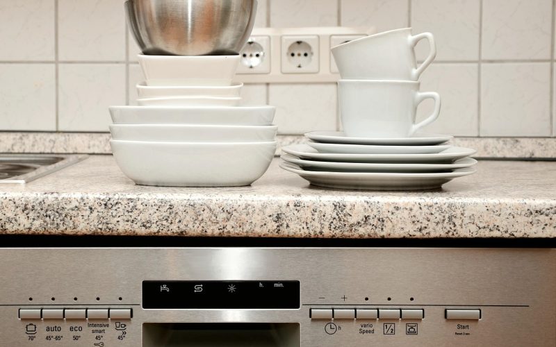 Een installateur plaatst een vaatwasser in een moderne keuken