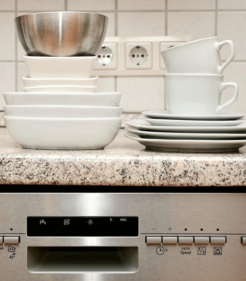 Een installateur plaatst een vaatwasser in een moderne keuken