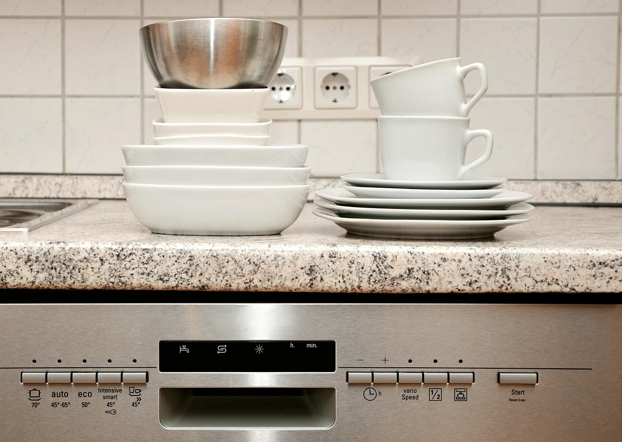 Een installateur plaatst een vaatwasser in een moderne keuken