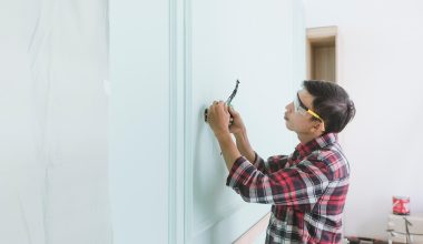 Persoon controleert een veiligheids checklist in een woning met rookmelder aan het plafond