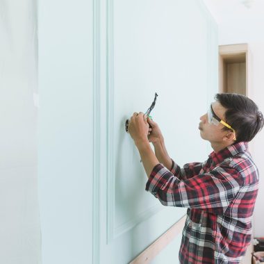 Persoon controleert een veiligheids checklist in een woning met rookmelder aan het plafond
