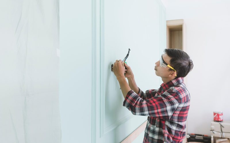 Persoon controleert een veiligheids checklist in een woning met rookmelder aan het plafond
