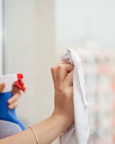 Iemand reinigt een doekluifel aan een huis met een zachte borstel en zeepwater